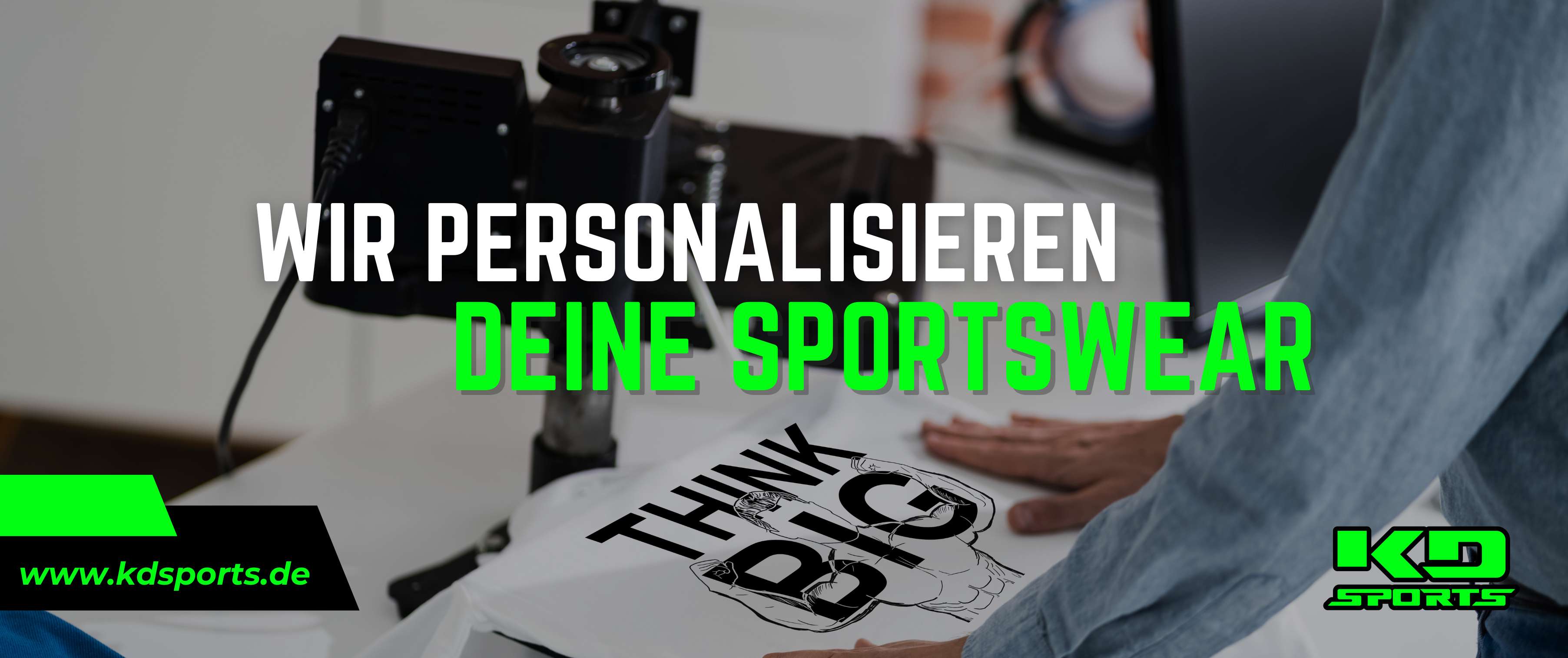 Eine Person personalisiert ein weißes T-Shirt mit dem schwarzen 'THINK BIG'-Motiv auf einer Druckmaschine. Das Bild bewirbt den Sportswear-Personalisierungsservice von KD Sports.